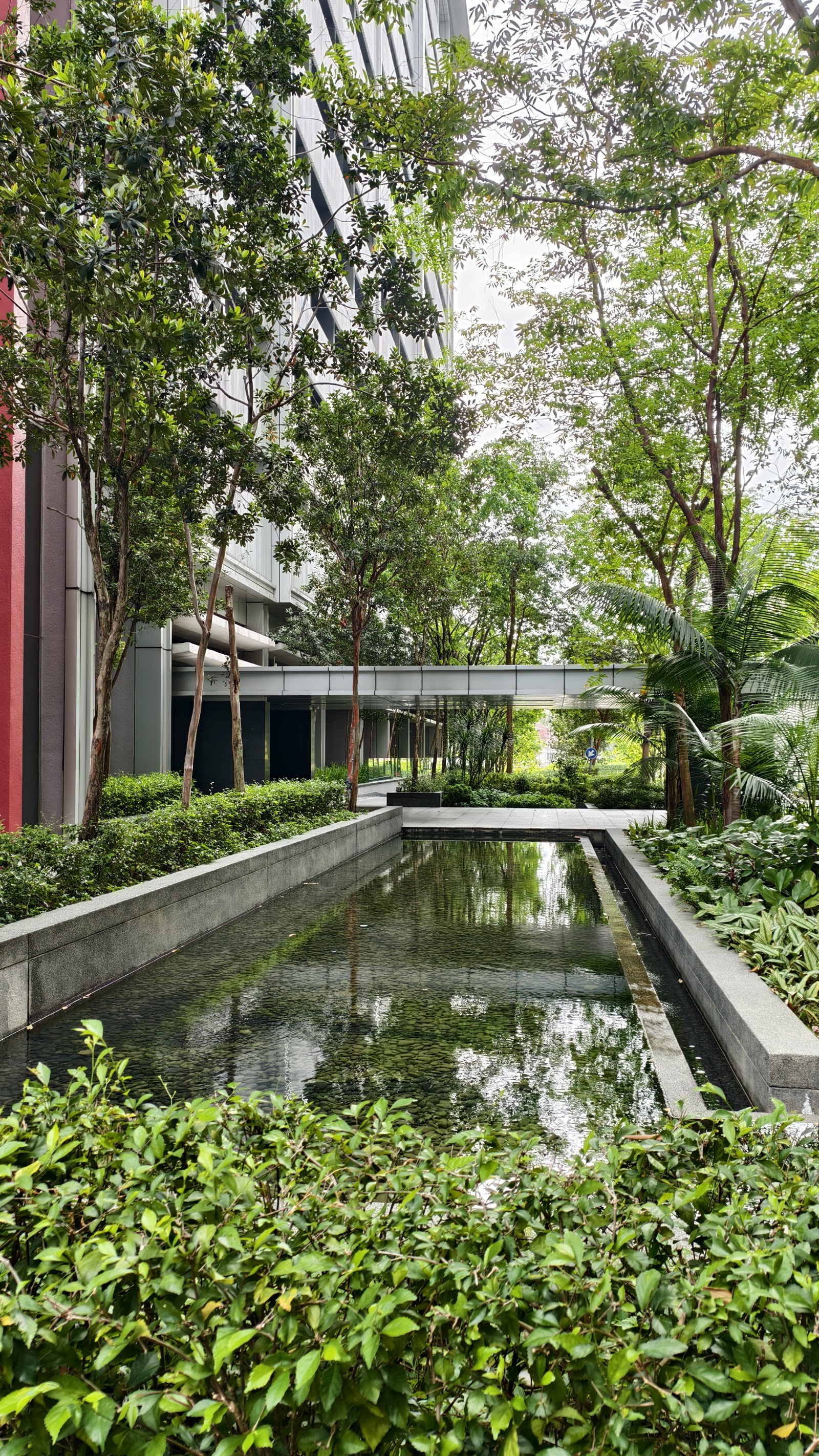 Dua Residency: A landscaped garden area featuring a reflective rectangular water channel, manicured trees, and shrubbery.