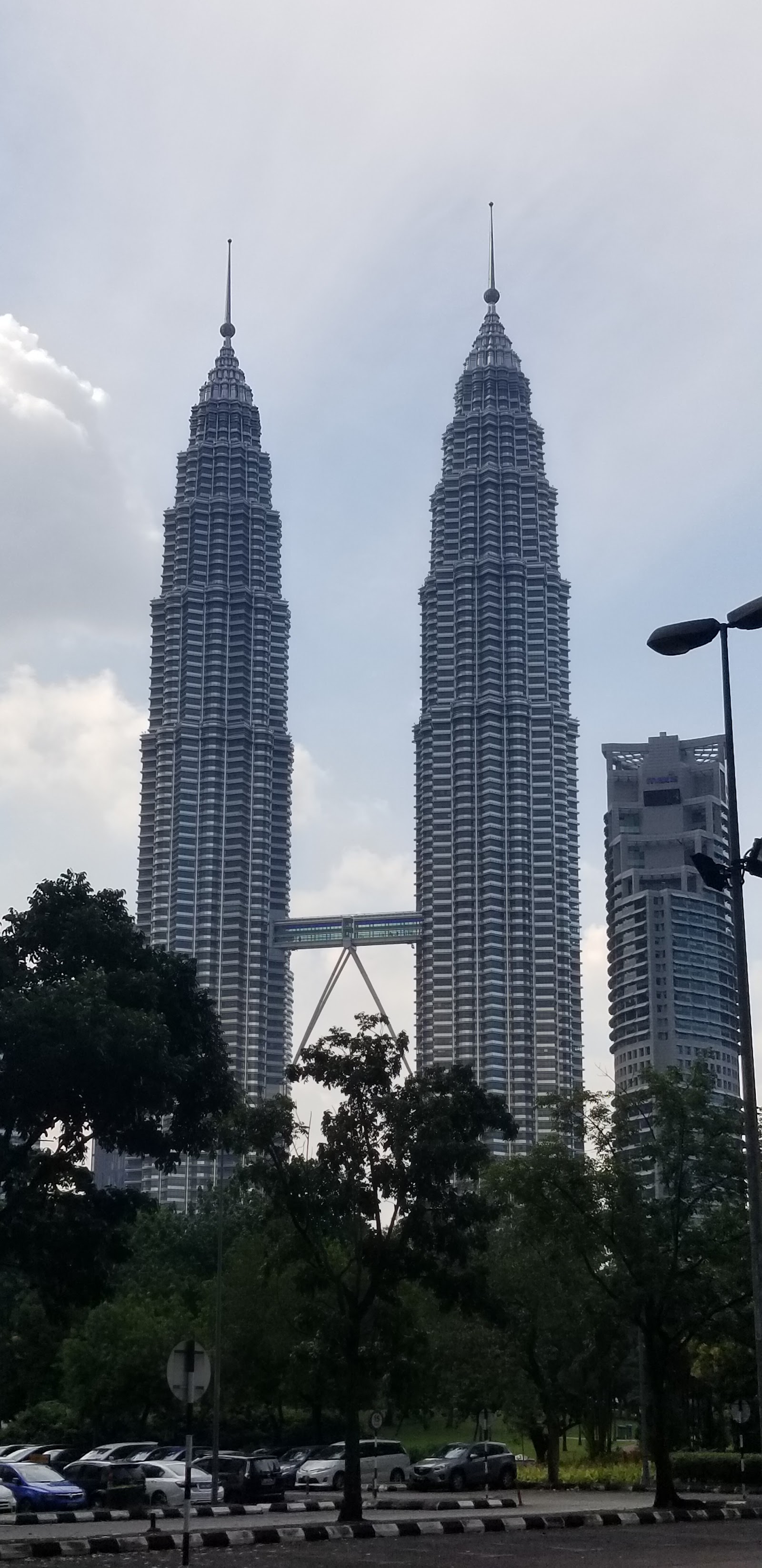 Park Seven: A view of the Petronas Twin Towers and a neighboring building seen through the trees of a park.