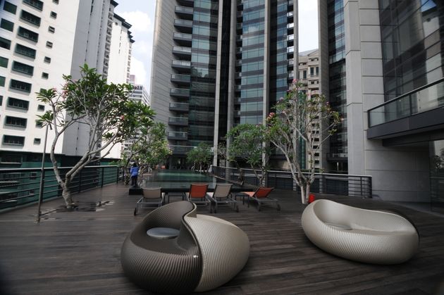The Troika: A rooftop pool and lounge area with modern furniture and trees, surrounded by high-rise residential towers.