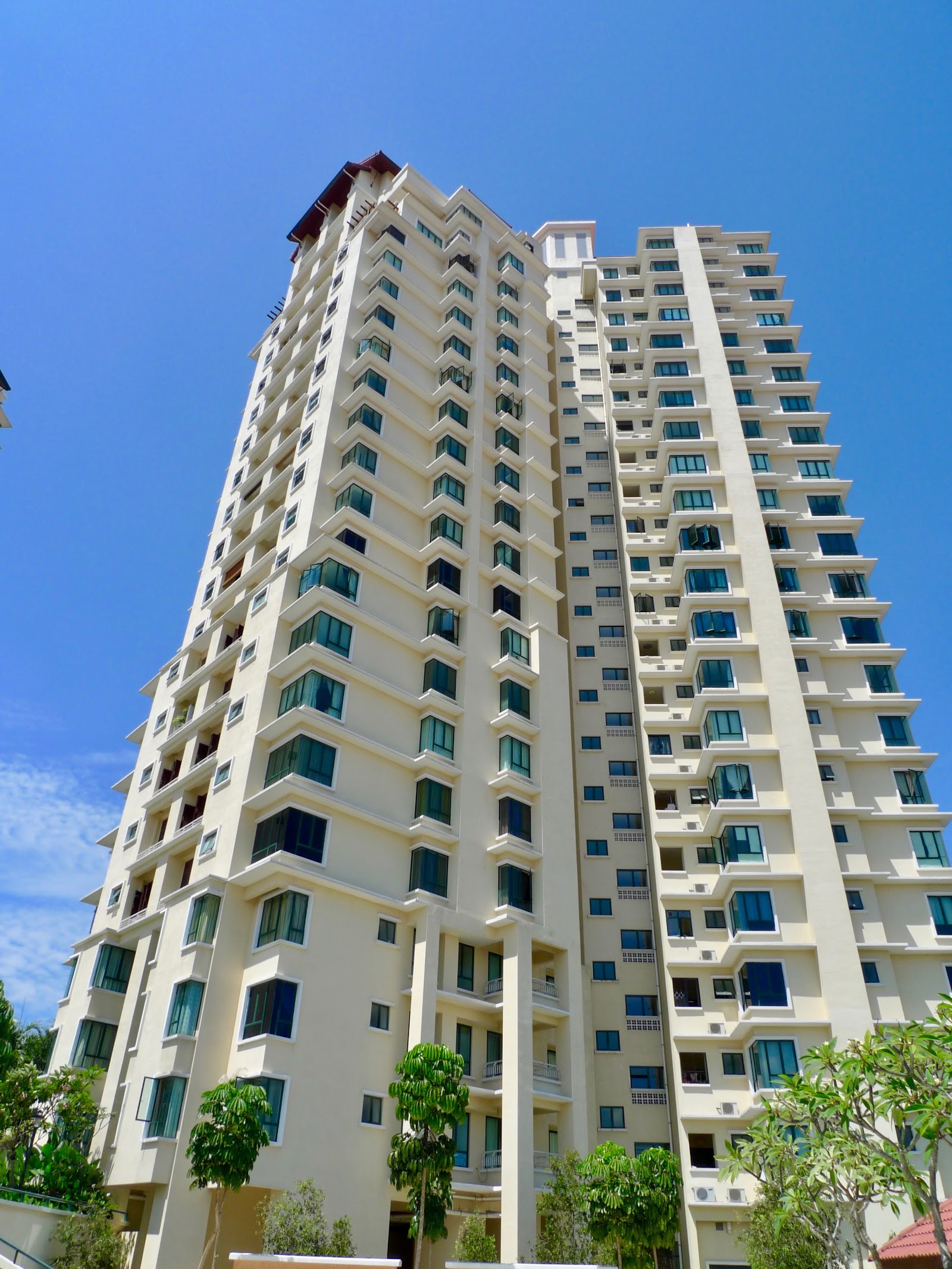 Nadia Parkfront: A low-angle shot of a tall, cream-colored residential tower against a clear blue sky, surrounded by trees at the base.
