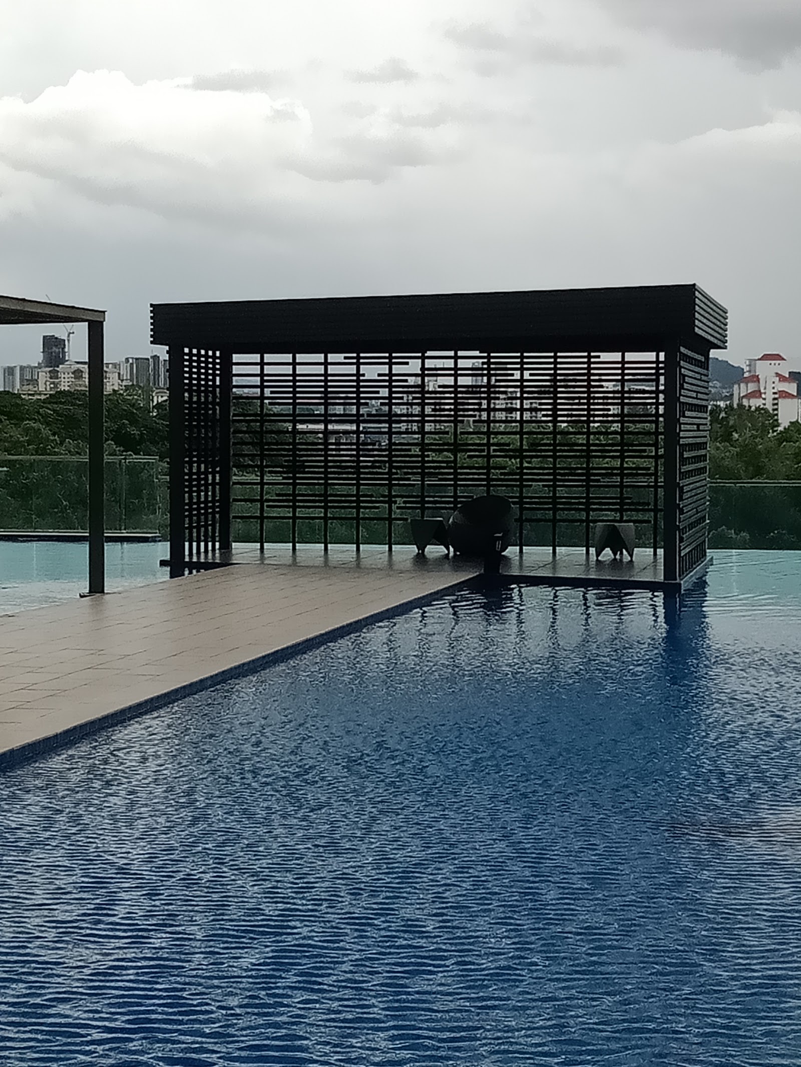 Parkhill Residence Bukit Jalil: A rooftop infinity pool with a modern pergola structure containing lounge chairs.