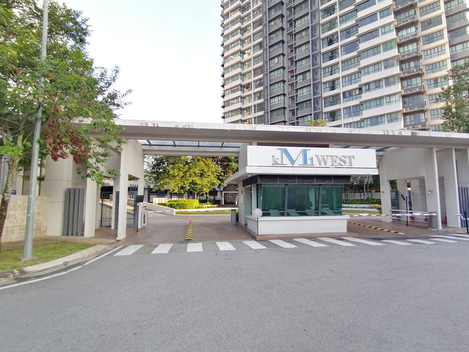 KM1: The entrance gate and security booth of the KM1 West residential development with the apartment tower visible in the background.