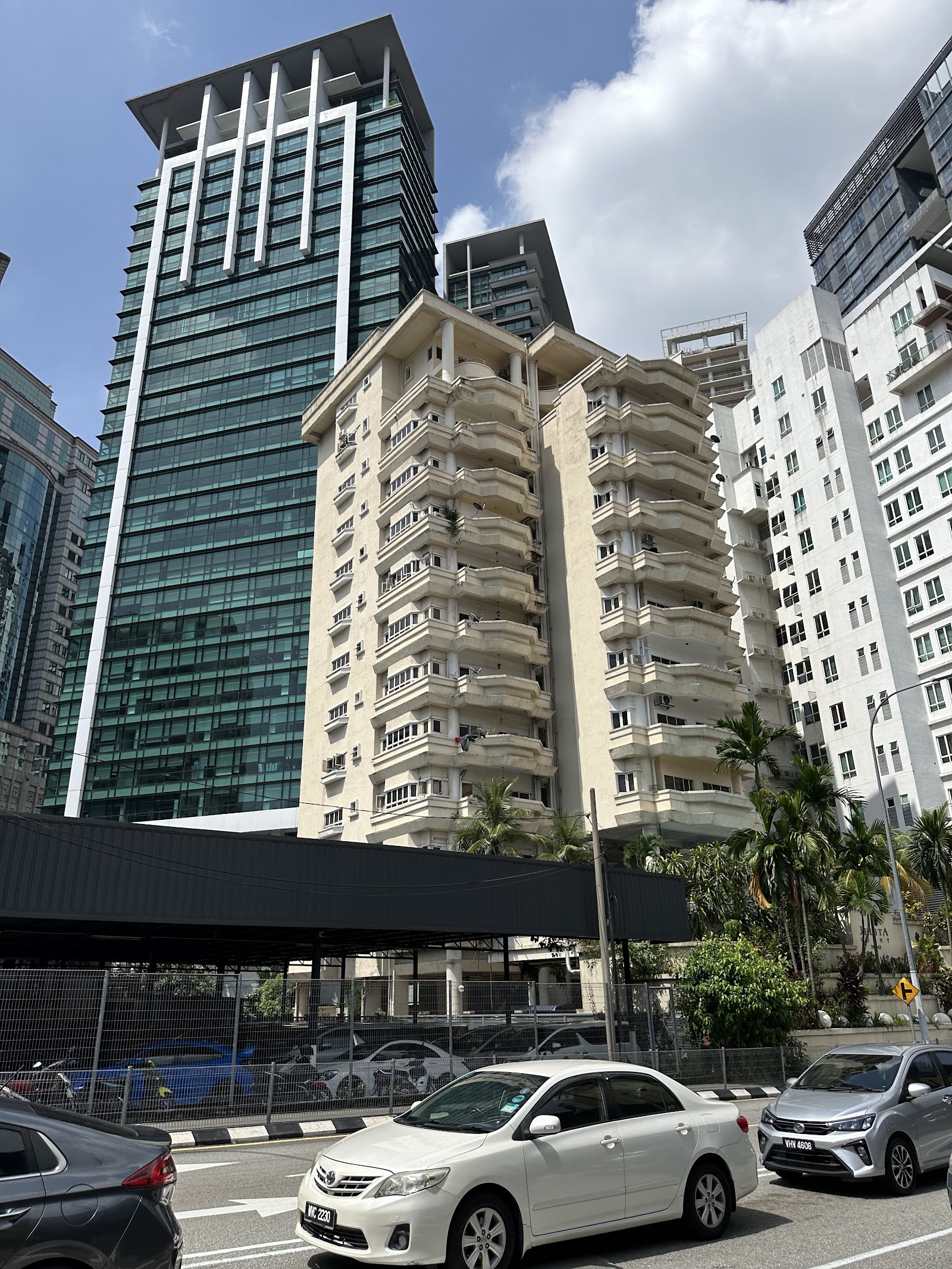 Jelita Court: A street-level view looking up at the facade of a residential building, Jelita Court, set against taller modern towers, with cars parked in the foreground.