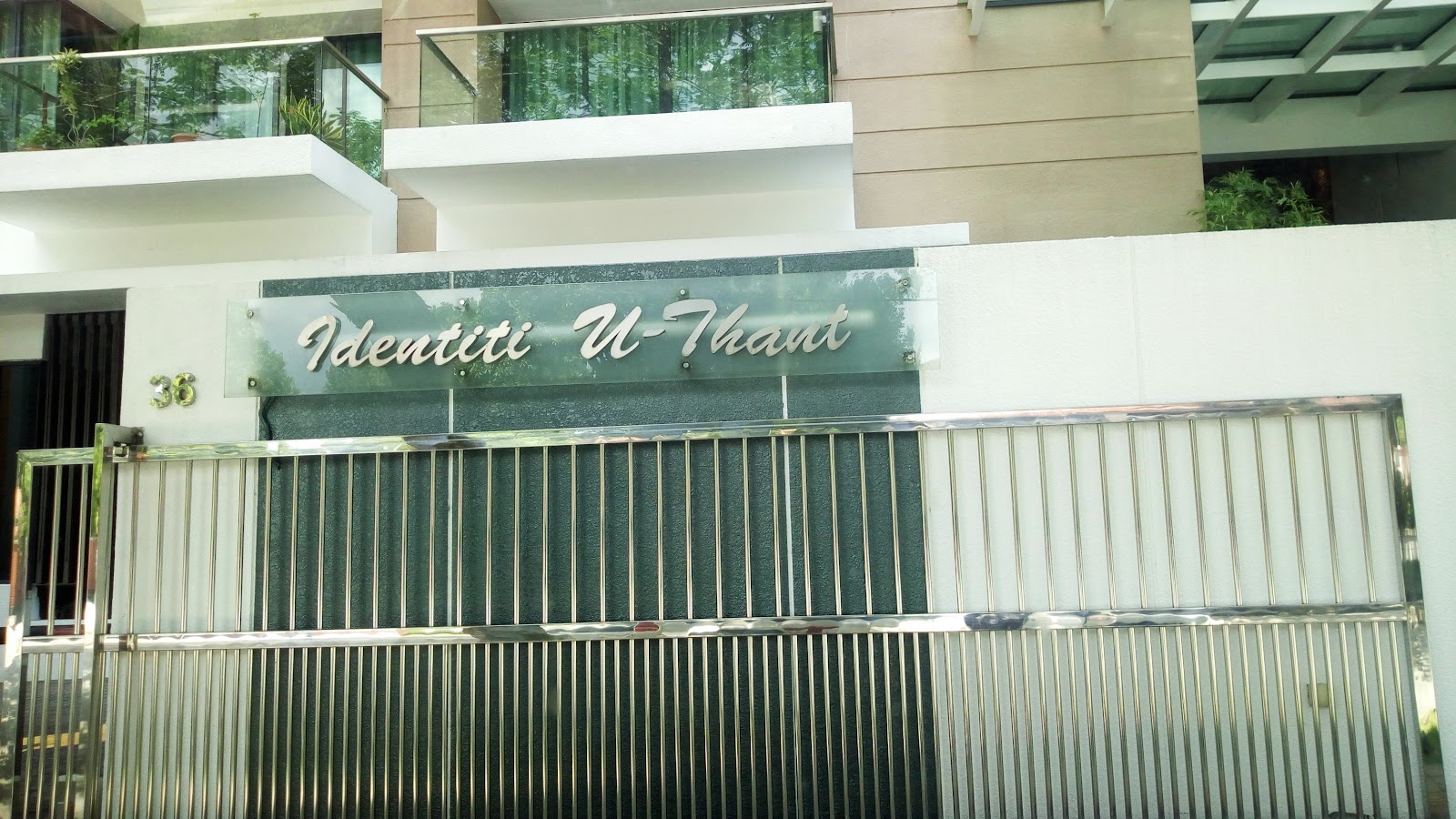 Identiti U-Thant: The entrance gate and facade of the Identiti U-Thant condominium building, with a glass railing and greenery visible on the upper balcony.