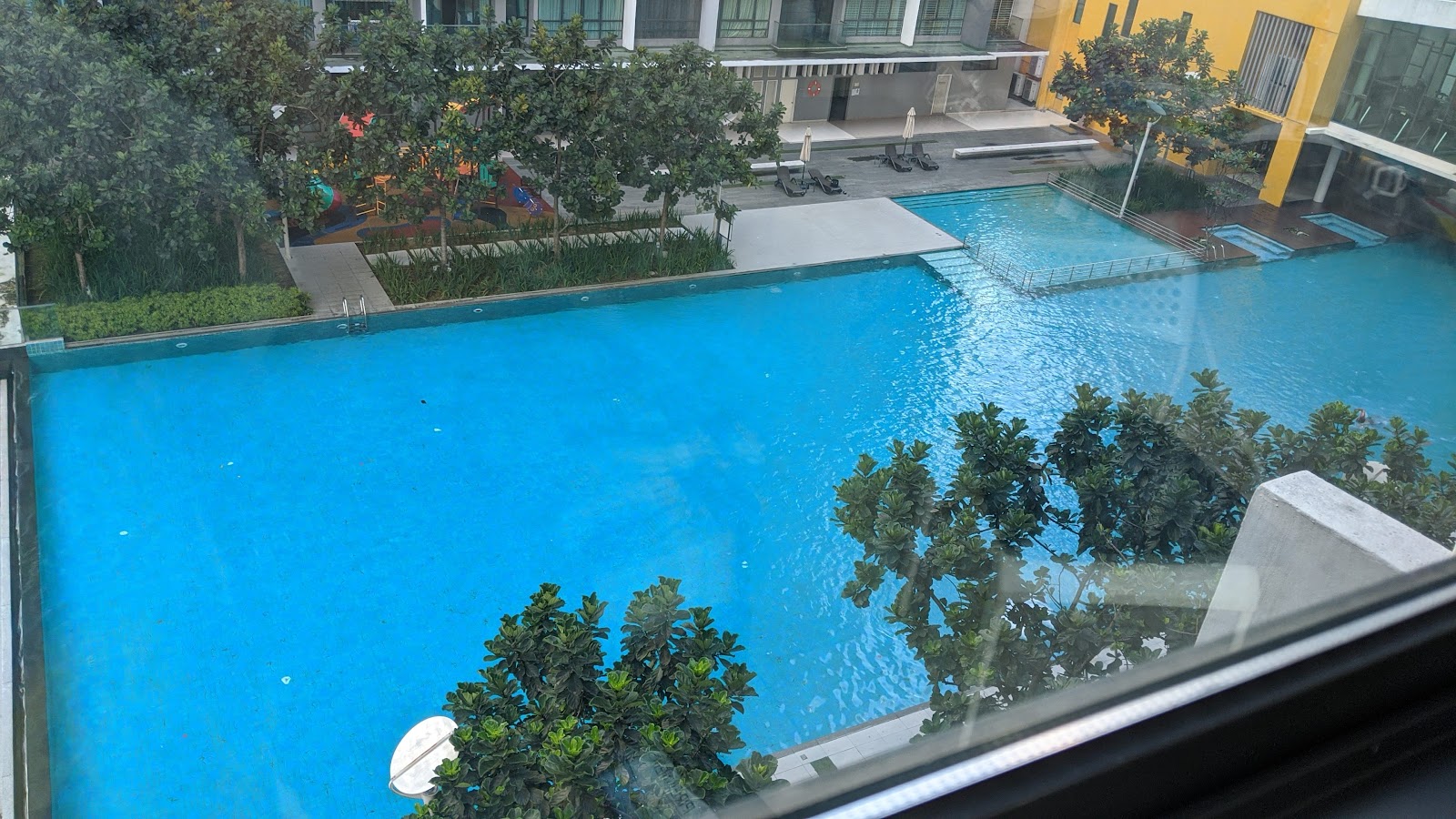 The Z Residence: An elevated view of a shared outdoor swimming pool and playground area within a residential complex.
