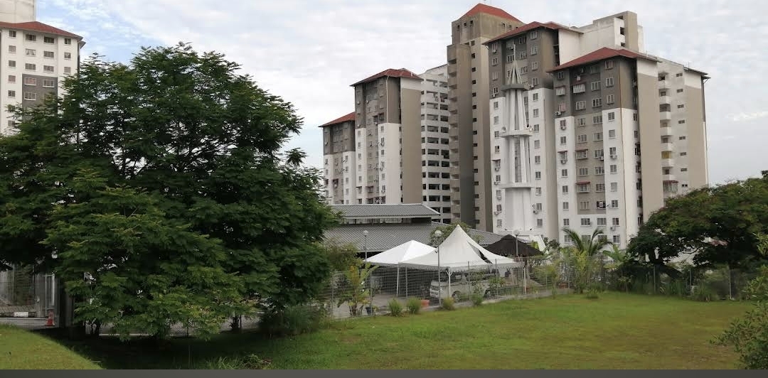 Apartment Seri Ceria 1: A view of the apartment buildings' facades with a green lawn and trees in the foreground.
