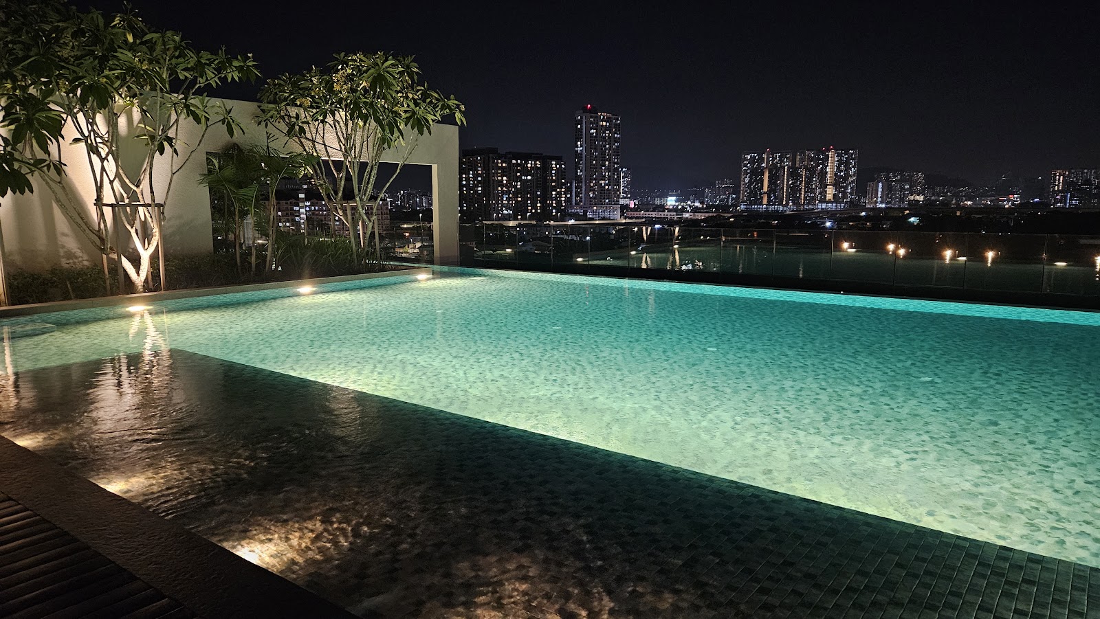 Impression U-Thant: A night shot of an illuminated rooftop infinity pool overlooking a city skyline.