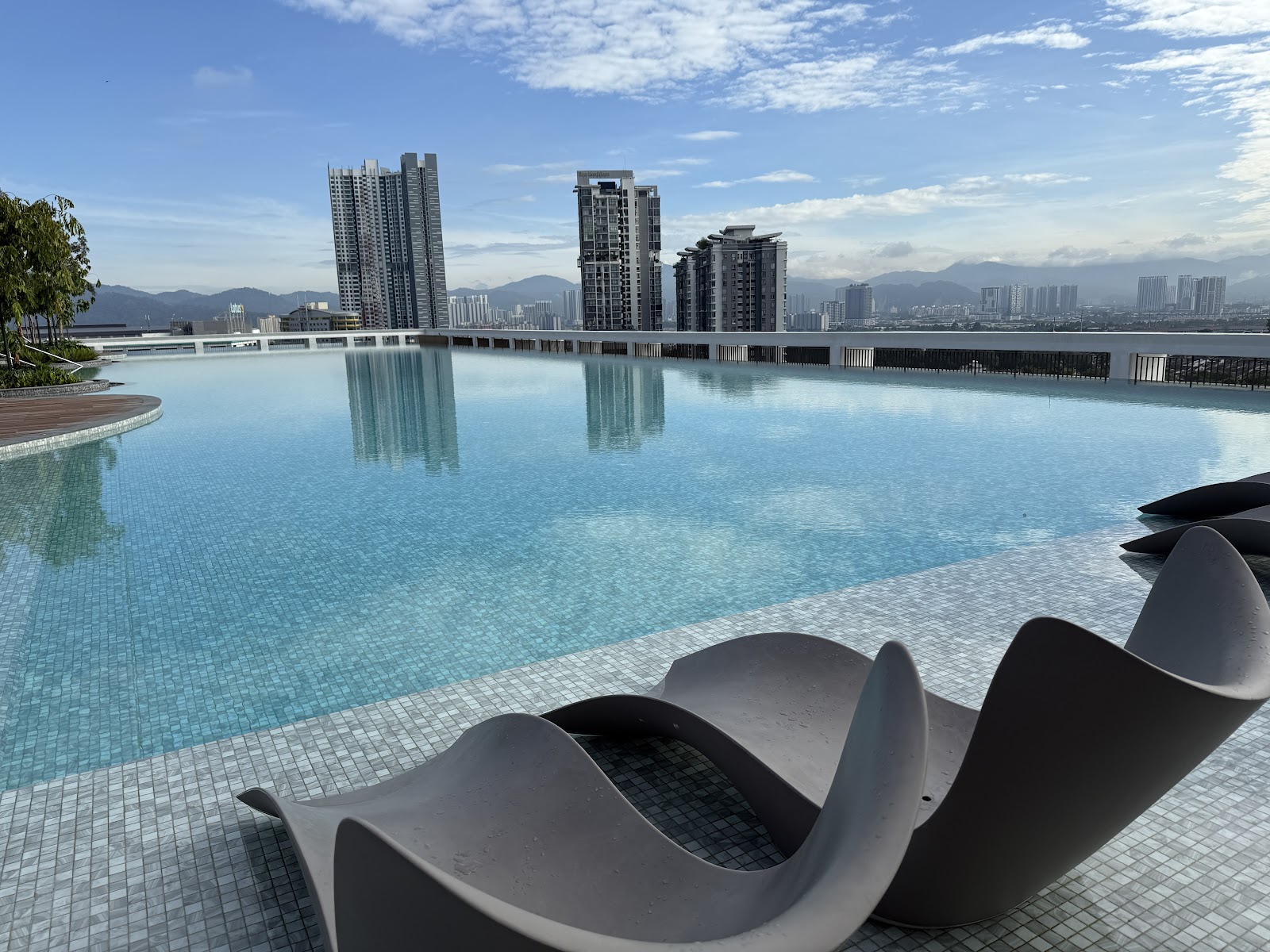 Park Place: A rooftop infinity pool with lounge chairs in the foreground overlooking a city skyline.