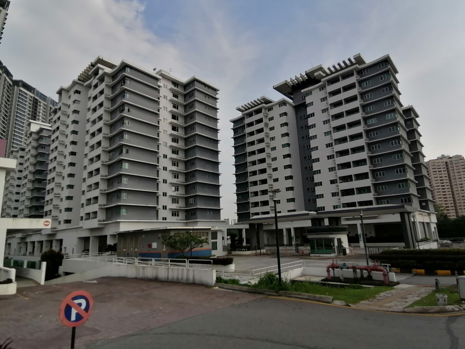 Kiara Residence 1: Two grey and white residential tower blocks with an entrance drive and parking area in the foreground.