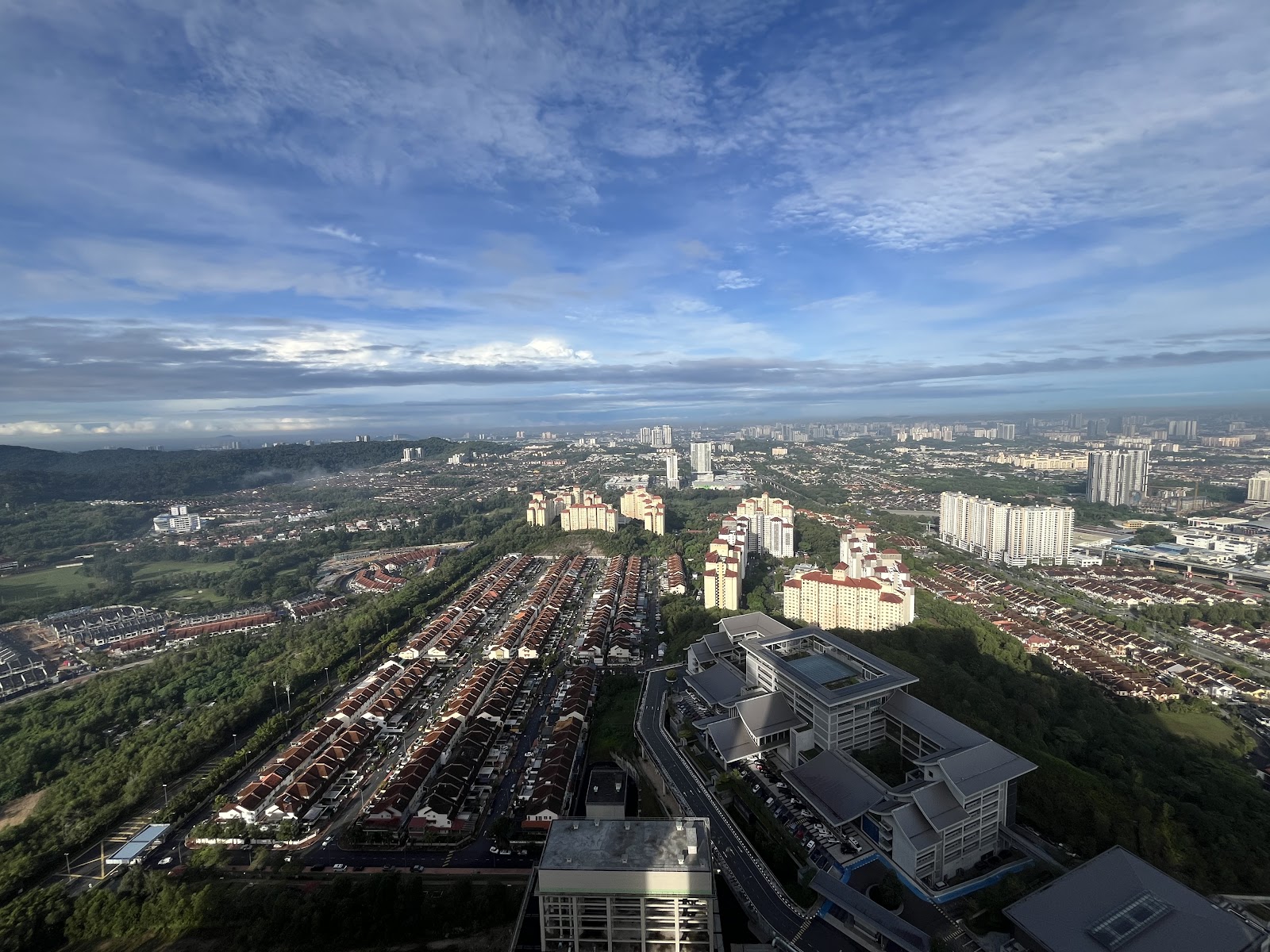 Mercu Jalil: A high-angle photograph showing a wide view of a city with residential housing, high-rise buildings, and a large institutional building in the foreground.