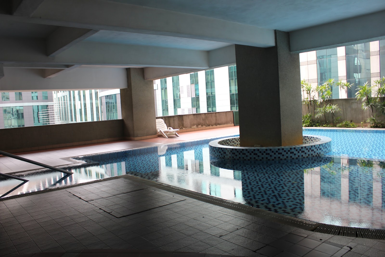Menara Avenue: An outdoor swimming pool with a circular structure and lounge chairs on a tiled deck.
