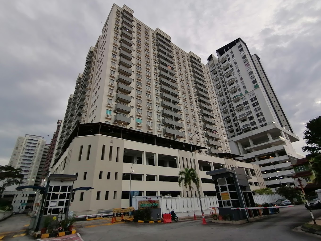 Kinrara Mas: A low-angle street view of the Kinrara Mas residential towers, showing the facade, entrance gate, and a lower annex building.