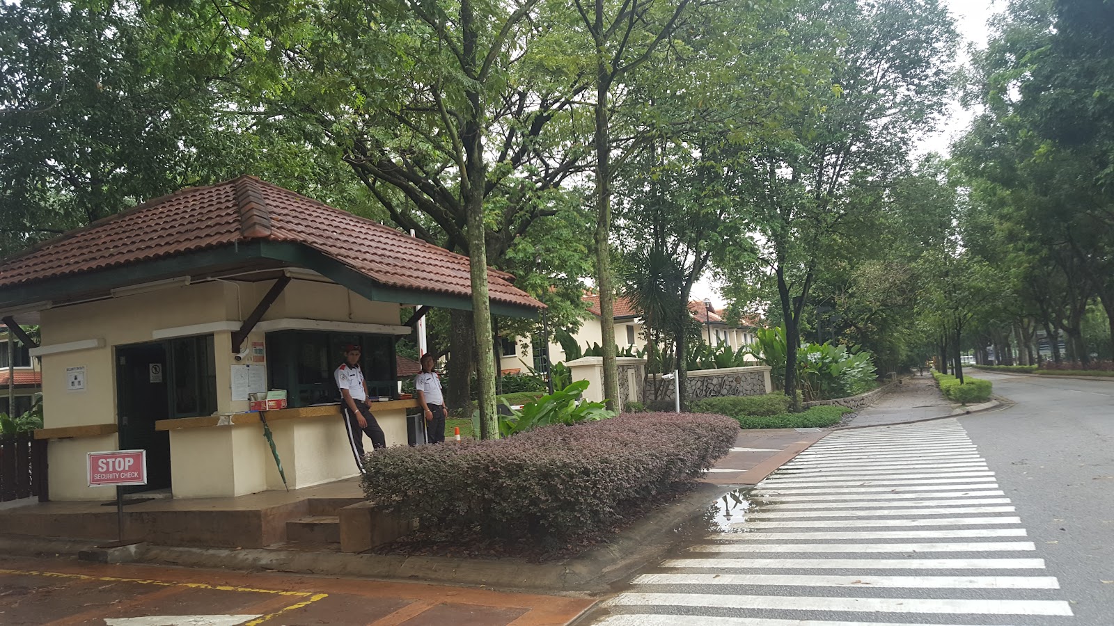 Nadia Parkfront: A security checkpost at the entrance of a residential development, flanked by trees and a driveway.