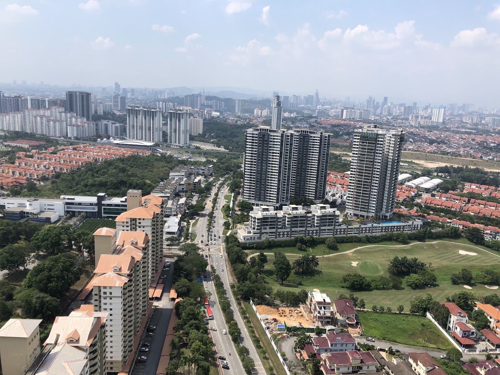 SkyLuxe On The Park @ Bukit Jalil: A panoramic aerial view looking out over a high-rise residential complex, a golf course, and a city skyline in the distance.