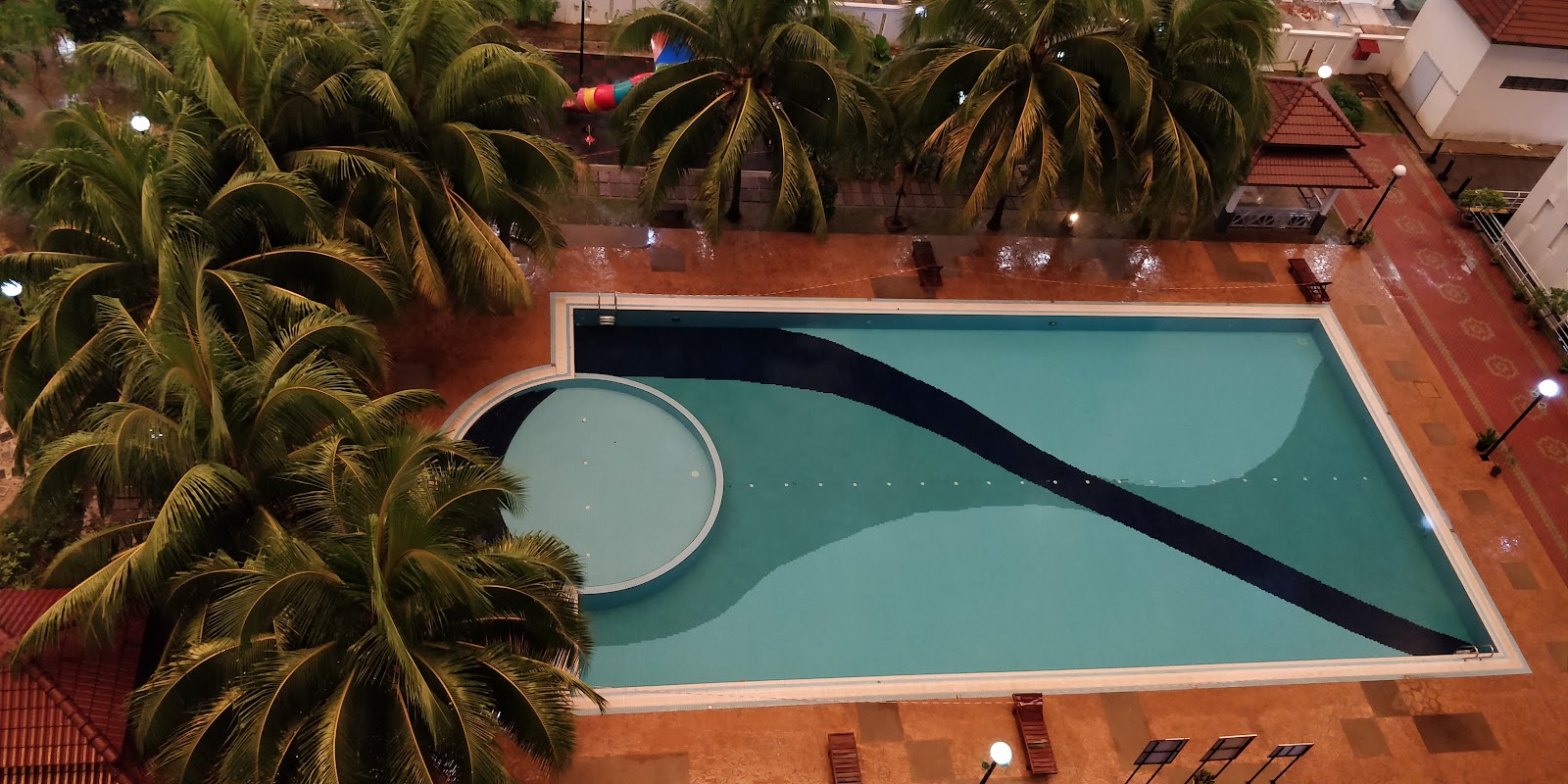 Kinrara Mas: An aerial view of a swimming pool with a circular annex, surrounded by palm trees and a tiled deck.