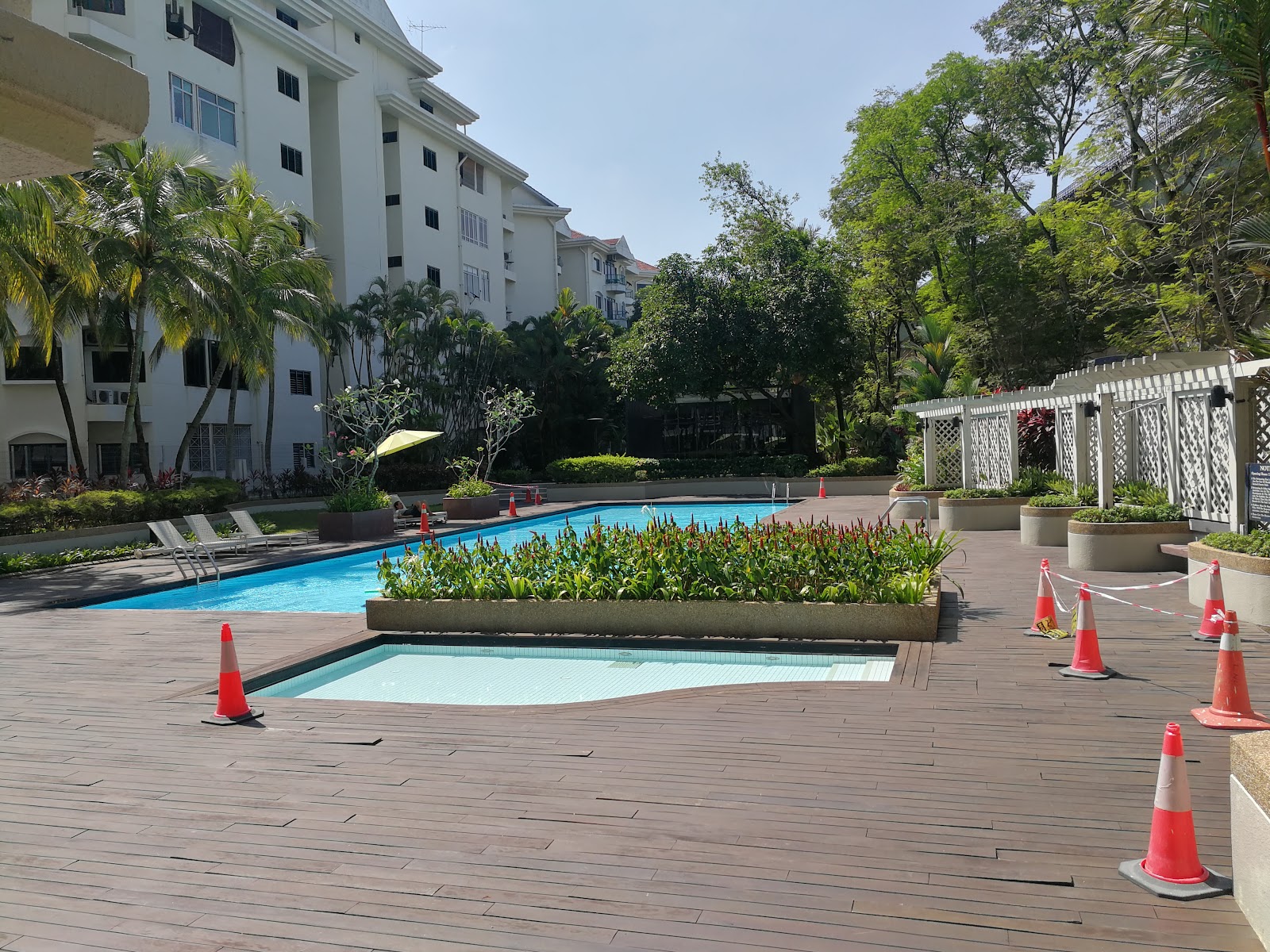 Tara Condominium: A swimming pool area with lounge chairs, surrounded by wooden decking, planters with greenery, and the white exterior of a condominium building.