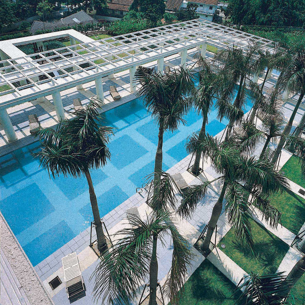 Hampshire Park: An aerial view of a swimming pool with a grid-style trellis roof and palm trees.