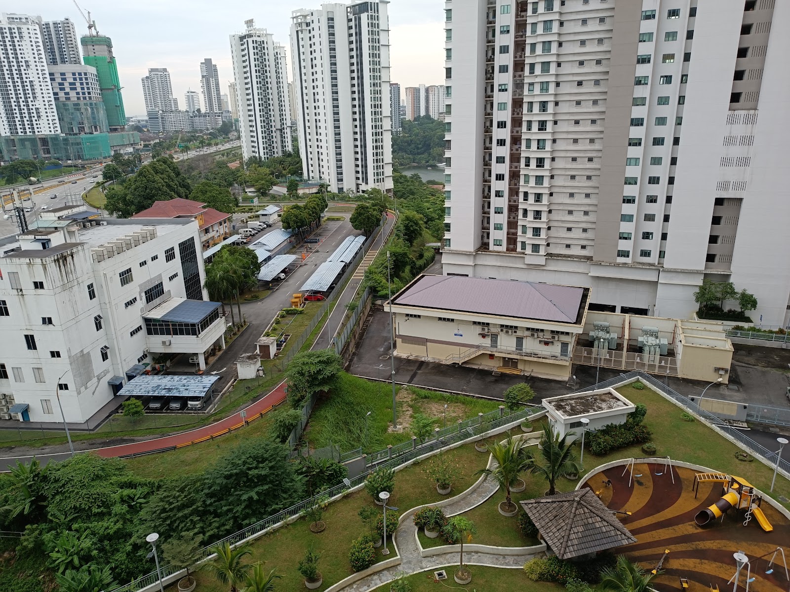 Residensi Laguna: An elevated view from a residential rooftop garden overlooking a substation, road, and surrounding high-rise buildings.