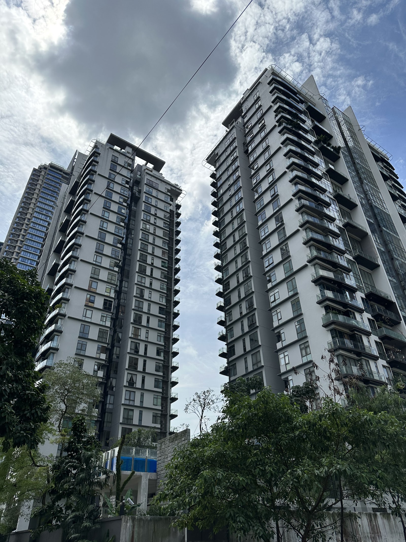 Suria Stonor: High-angle exterior shot of a tall, grey and white residential tower complex with balconies.