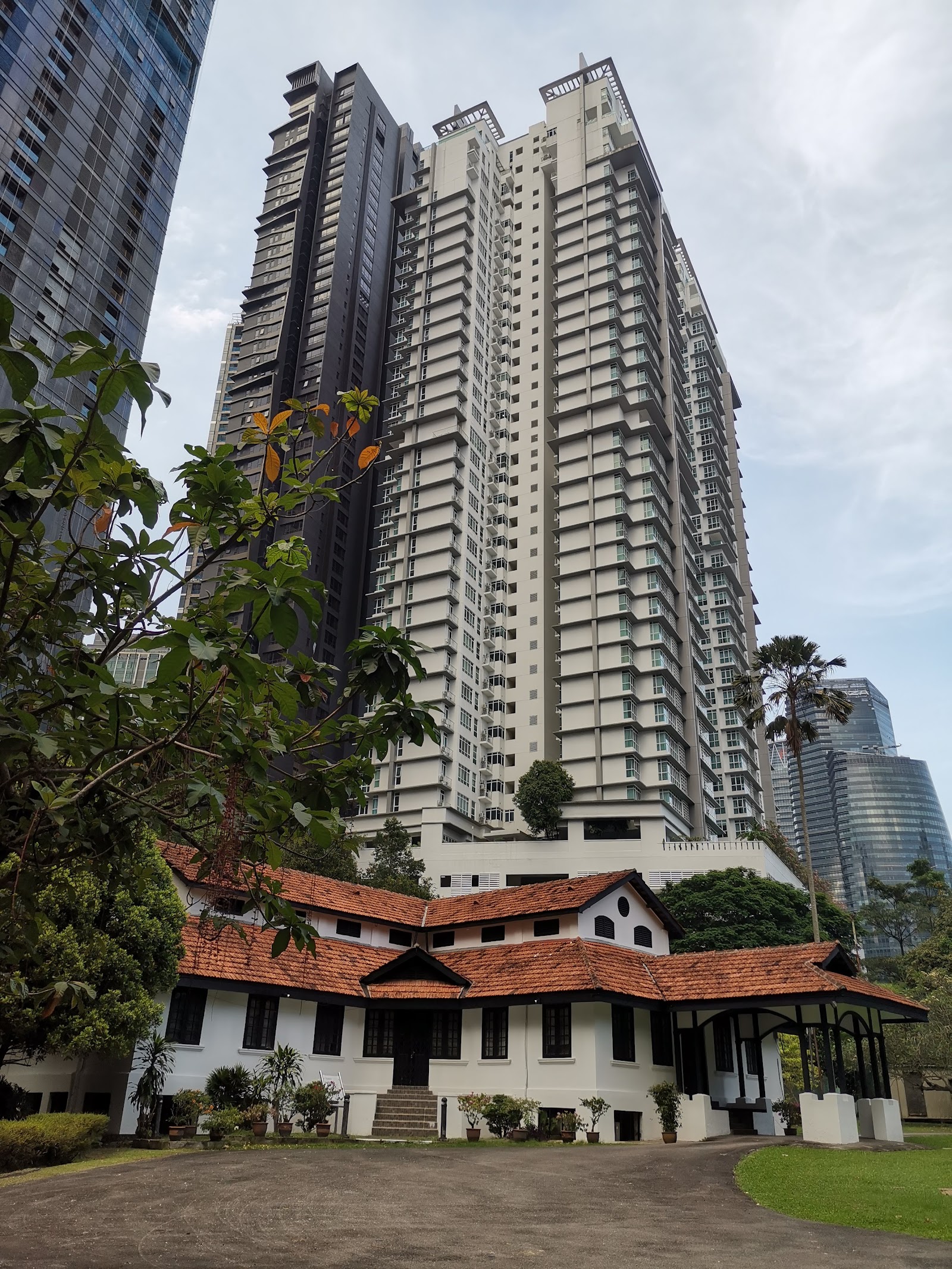 The Pearl: A white colonial-era house with an orange tile roof in the foreground, set against a backdrop of modern high-rise residential towers and other skyscrapers.