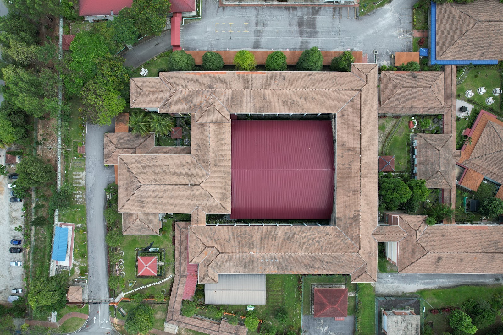 De Rozelle: Aerial top-down view of a complex building with a large central courtyard and brown tiled roofs, surrounded by greenery, roads, and parking areas.
