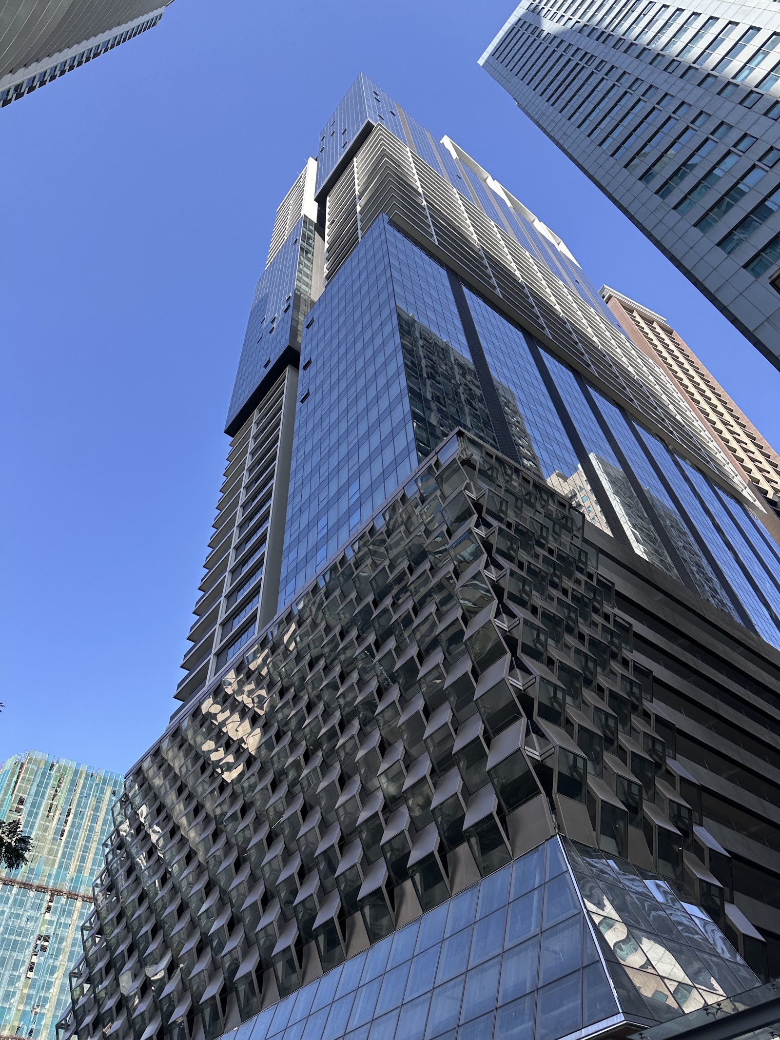 Platinum Victory Suites: A low-angle view of a modern high-rise building with a glass and textured metal facade against a clear blue sky.