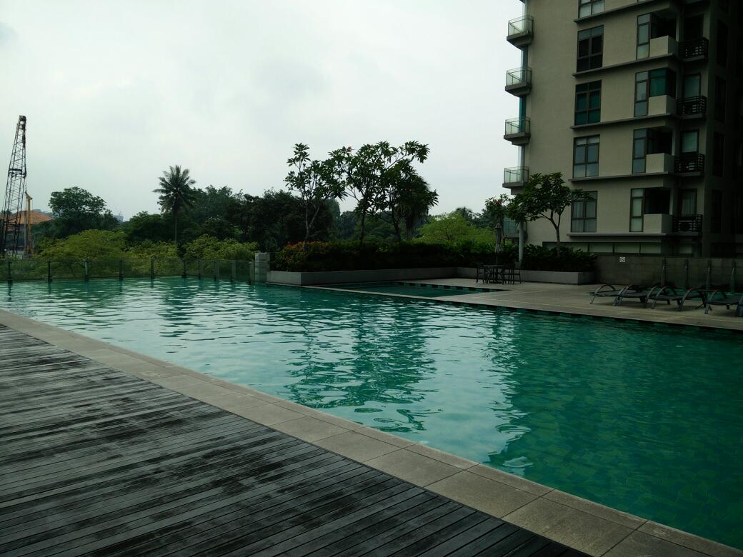 Suria Stonor: An outdoor swimming pool with a wooden deck and adjacent apartment building.