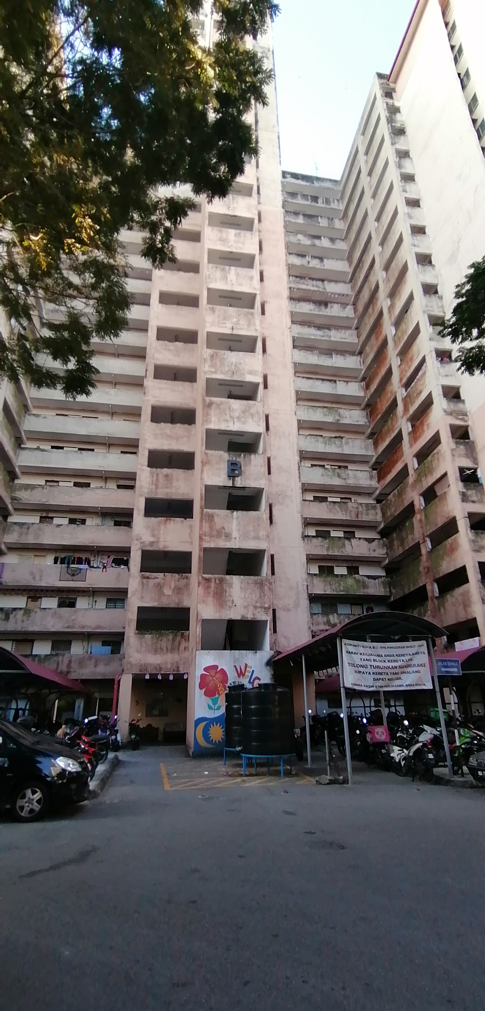 PPR Pinggiran Bukit Jalil: A low-angle photograph of a tall, weathered apartment block facade with multiple wings and open corridors.