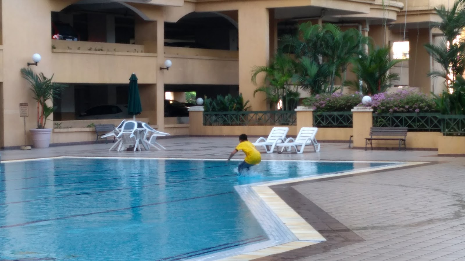 Prima Duta: A swimming pool with lounge chairs and a person in the water at a resort.