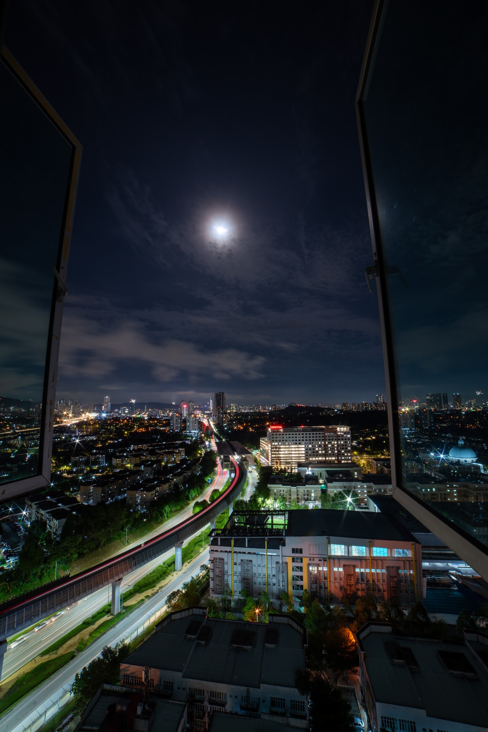 Casa Residenza @ Kota Damansara: A night view from a high vantage point looking out over a city with illuminated roads, buildings, and the moon in the sky.