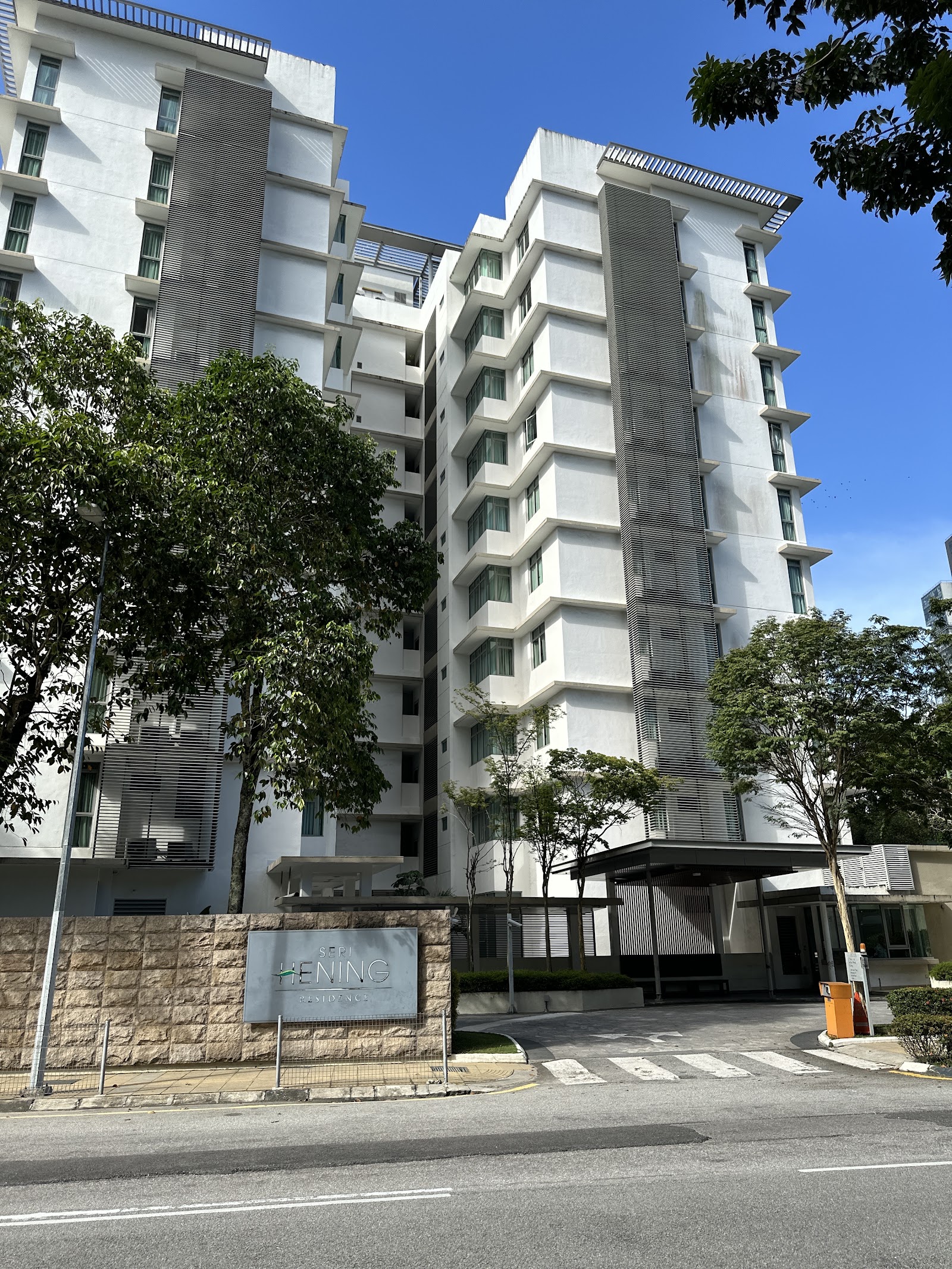 Seri Hening Residence: A view of the exterior facade of the Seri Hening Residence high-rise buildings from the street, showing a stone sign and landscaping.