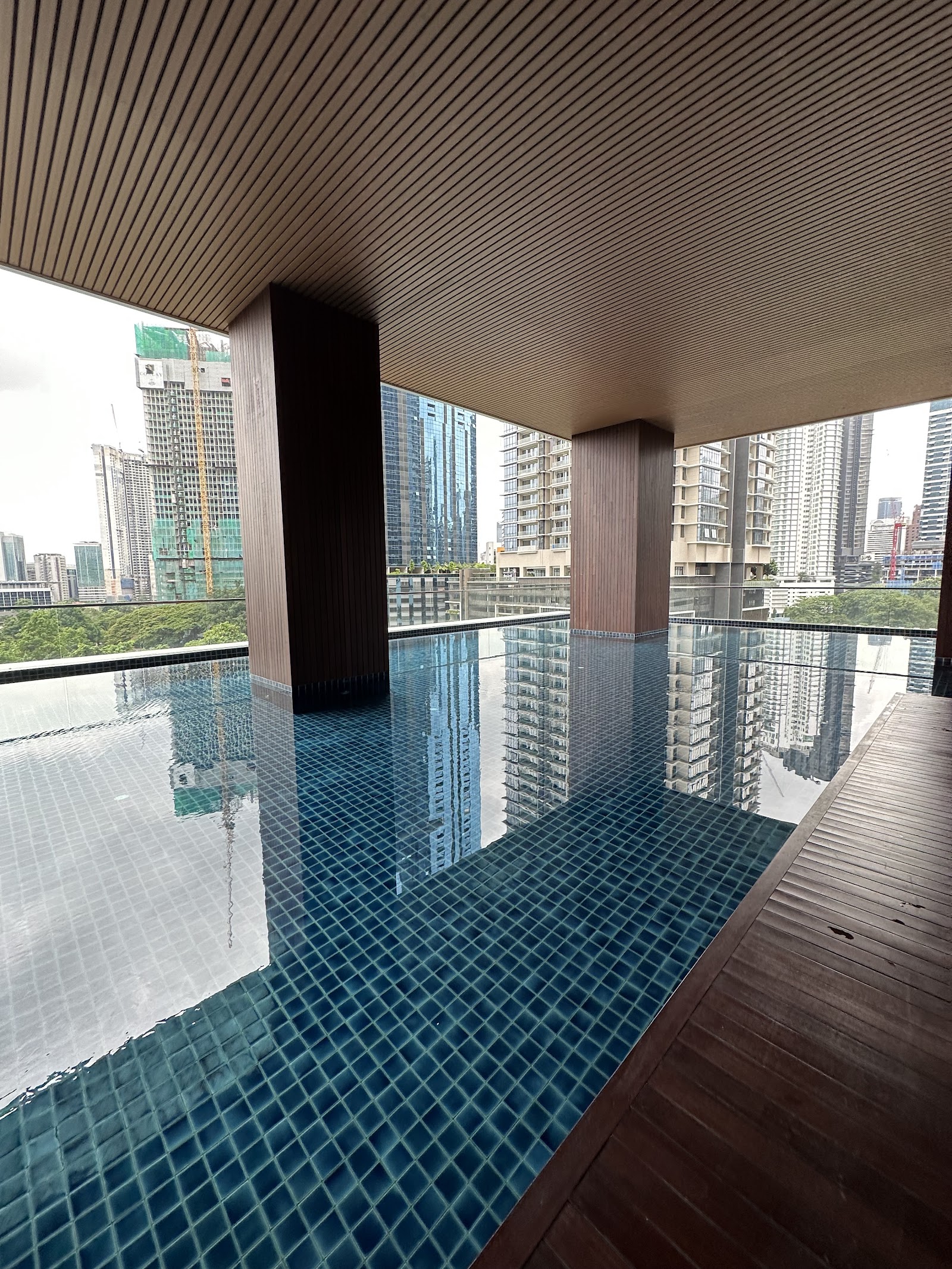 10 Stonor: A covered infinity pool with blue tiles and wooden deck, overlooking a city skyline.