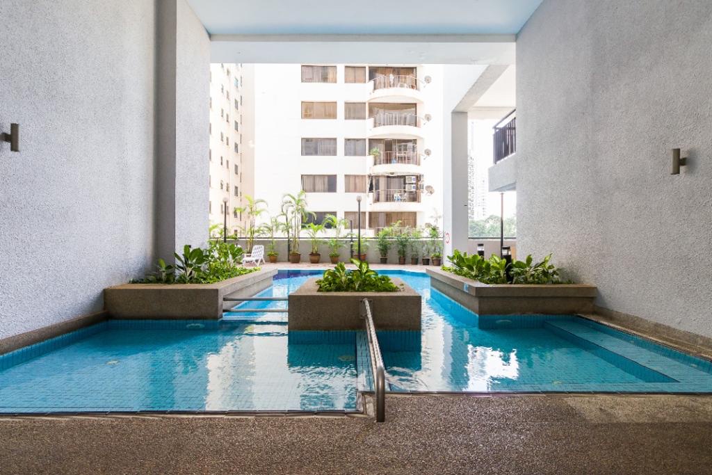 Seri Bukit Ceylon: A swimming pool in a courtyard with planters and a white building facade in the background