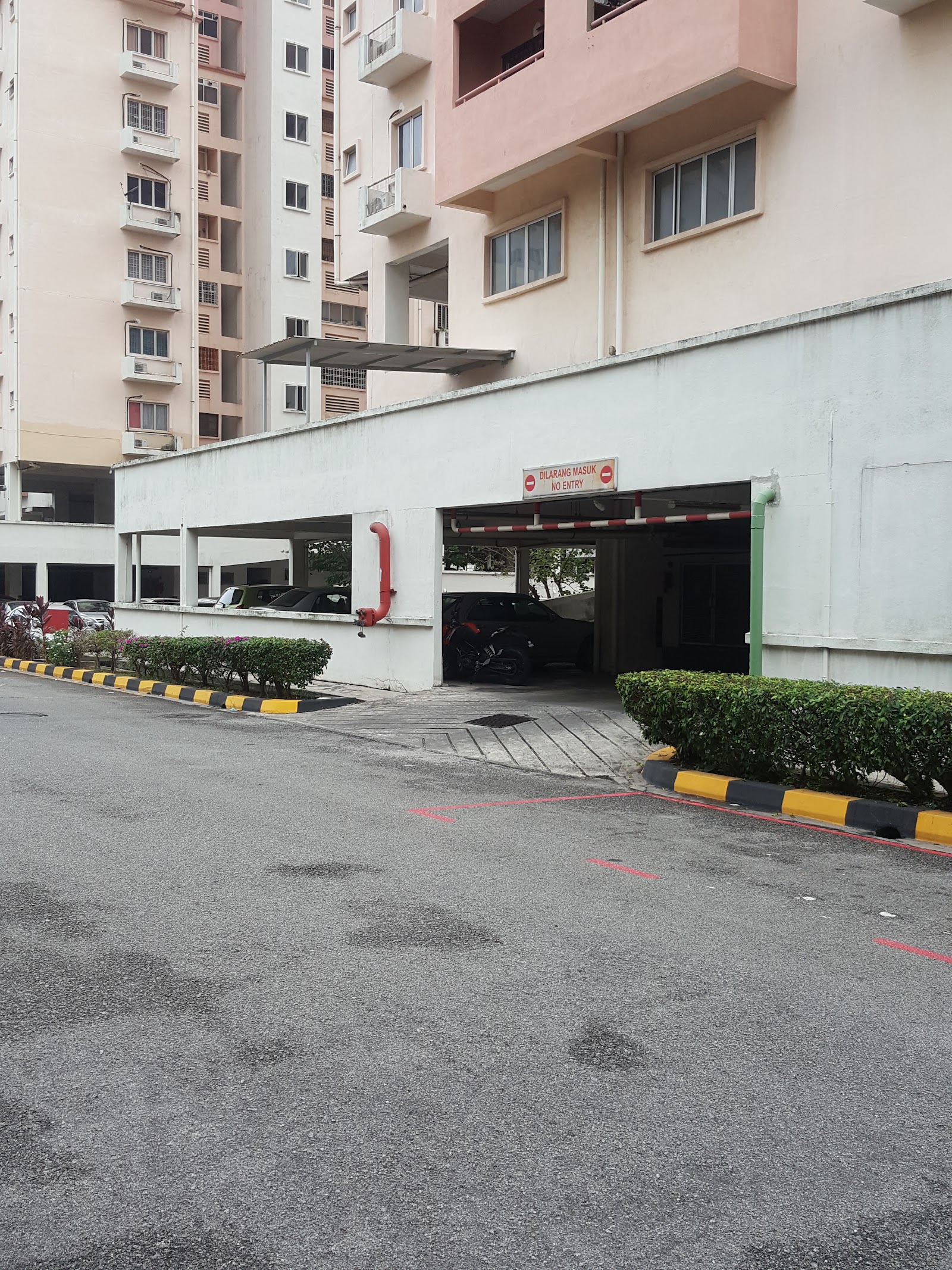 Pangsapuri Sri Rakyat: The exterior of a residential development, showing a ground-level car park entrance with a 'No Entry' sign and apartment blocks in the background.