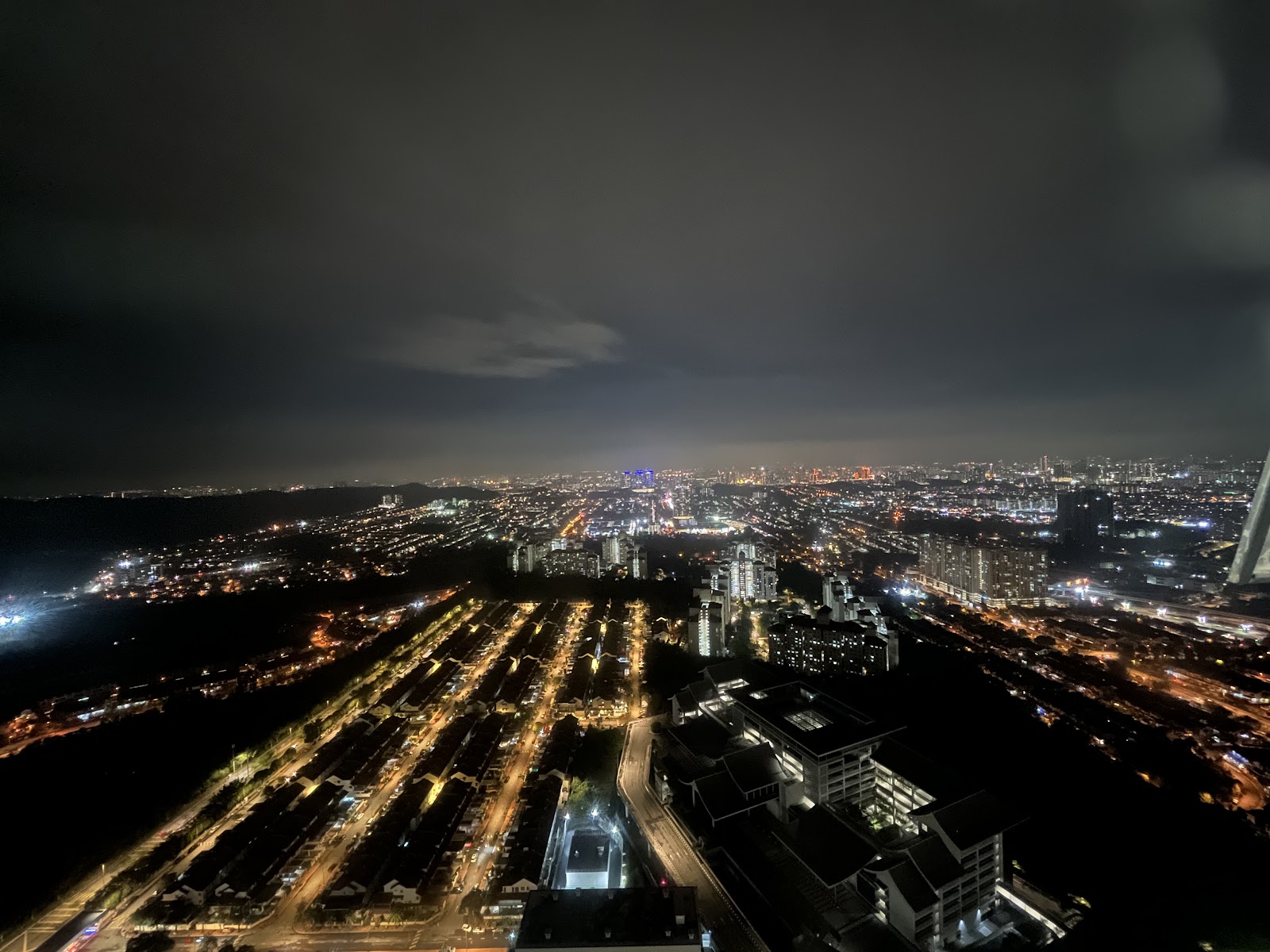 Mercu Jalil: A night view overlooking a city illuminated by streetlights and buildings, taken from a high vantage point.