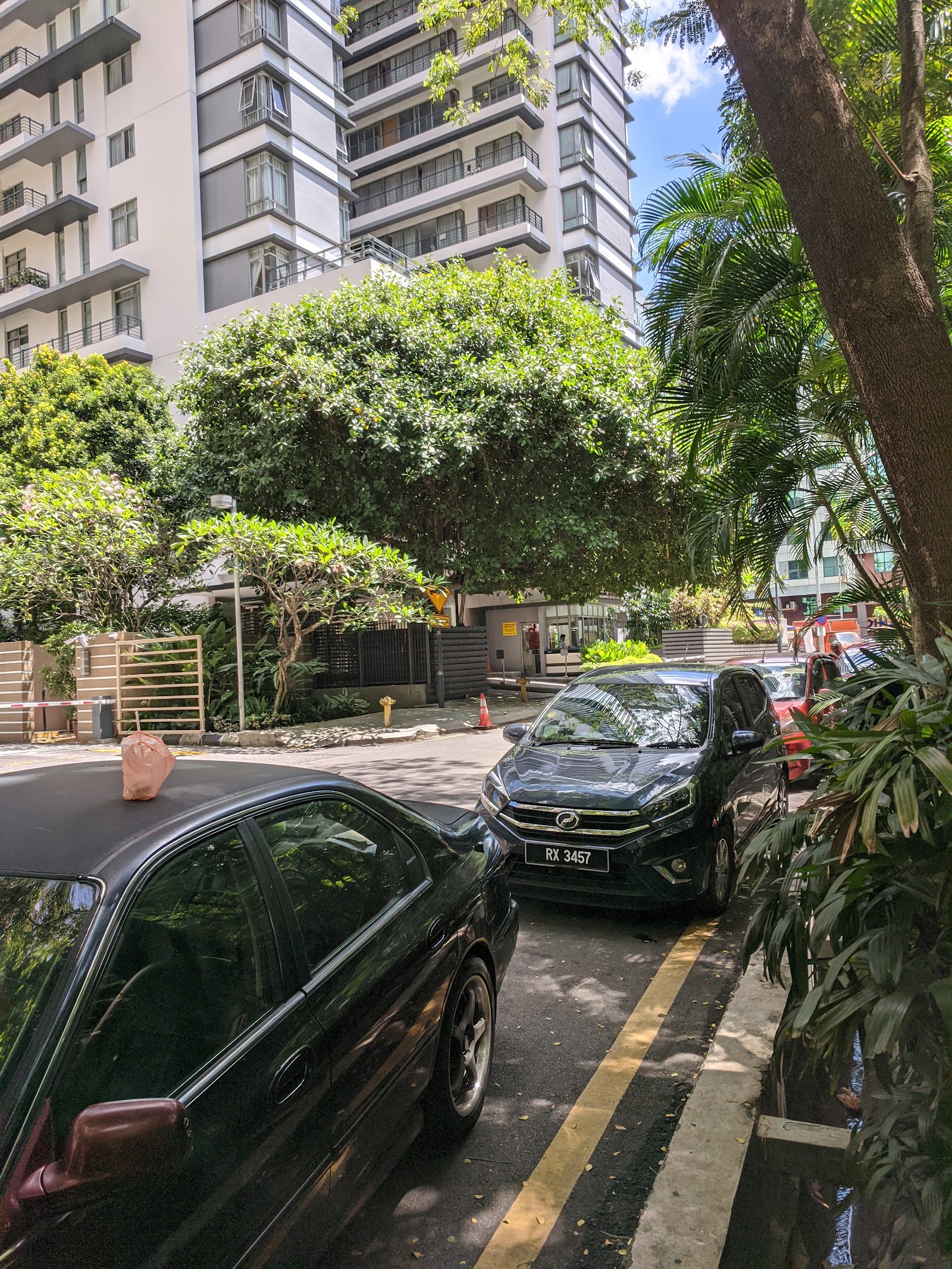 2 Hampshire: A view of a high-rise residential building and its lush green landscaping with several cars parked along the driveway.