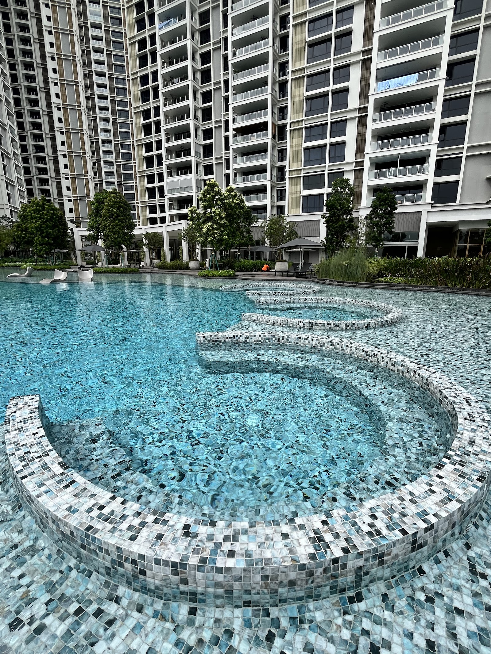 Park Regent by the Water: A swimming pool with mosaic-tiled tiers at a residential complex, with high-rise apartment towers in the background.