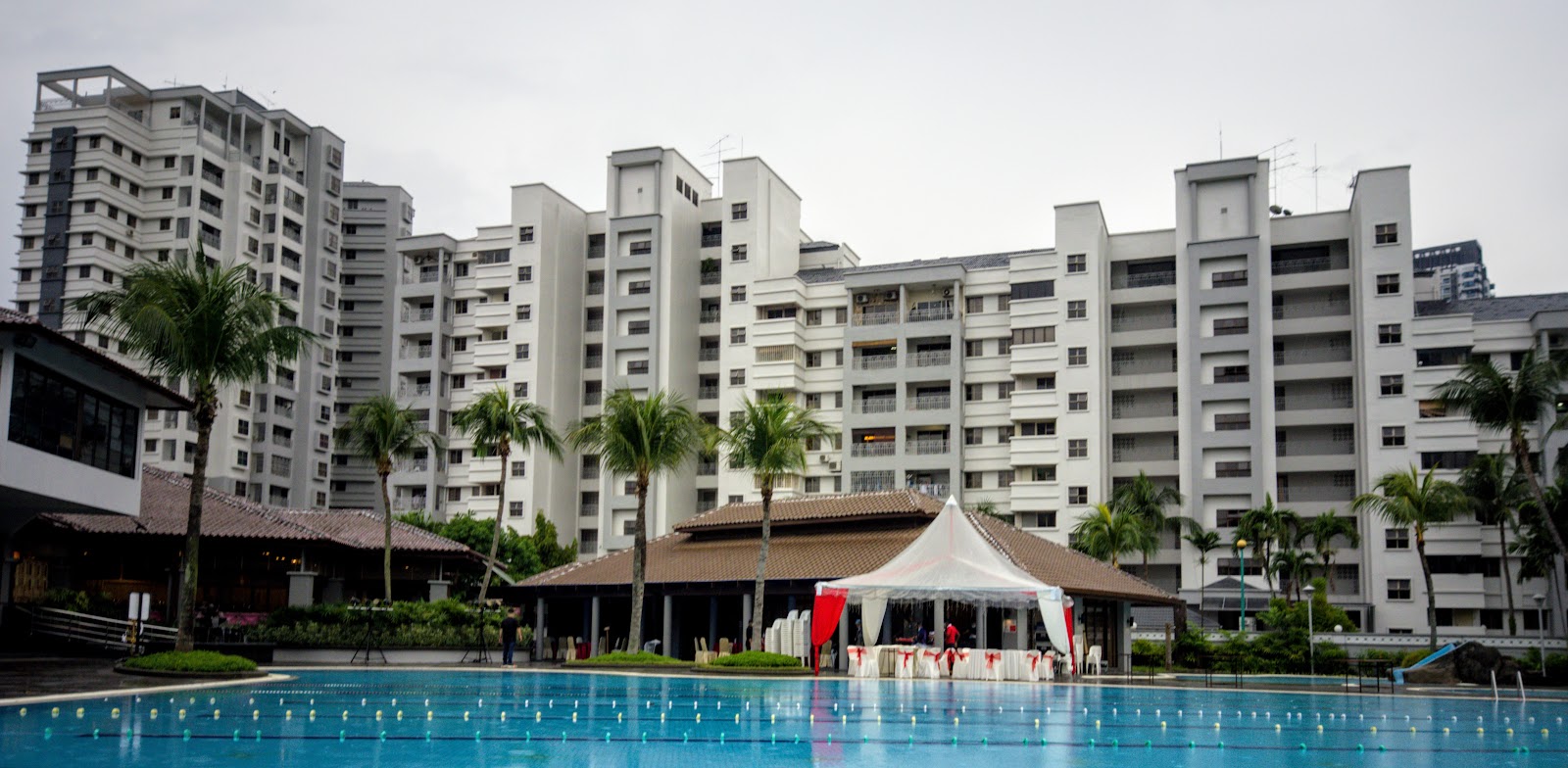 PALMVILLE RESORT CONDOMINIUM: A large swimming pool and a function area with a white tent in the foreground, with the resort condominium buildings and palm trees in the background.