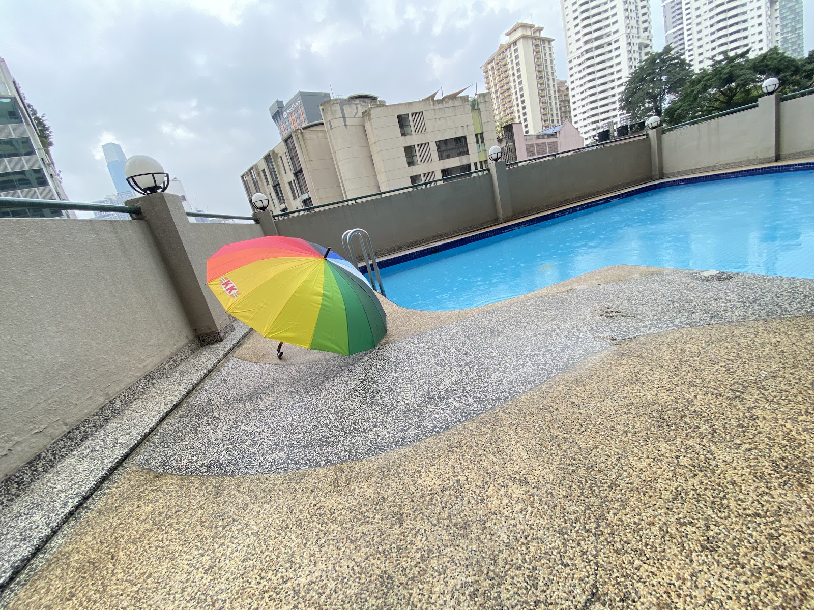 Seri Raja Chulan: A rooftop swimming pool with a rainbow umbrella resting on the deck, set against a backdrop of city buildings.