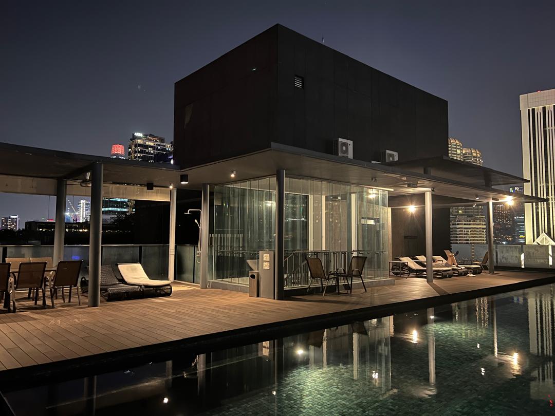 Dedaun Condominium: A rooftop infinity pool with lounge chairs and a glass-walled sauna or steam room at night.