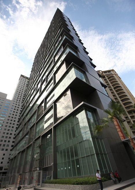 Vipod Residence: A low-angle view of the dark, modern facade of a high-rise building with large glass windows, set against a blue sky with other buildings in the background.