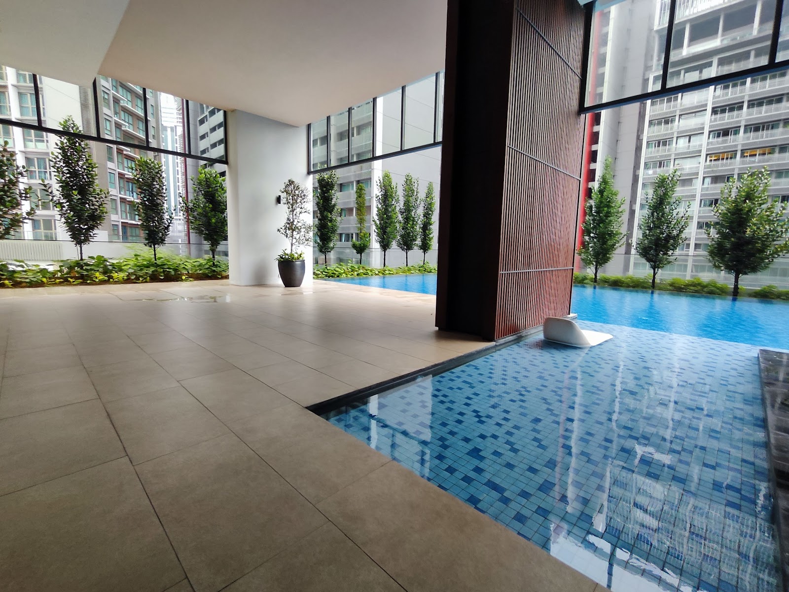 ARIA Luxury Residence: An outdoor swimming pool area with blue tiles and a tiled deck surrounded by manicured trees and landscaping.