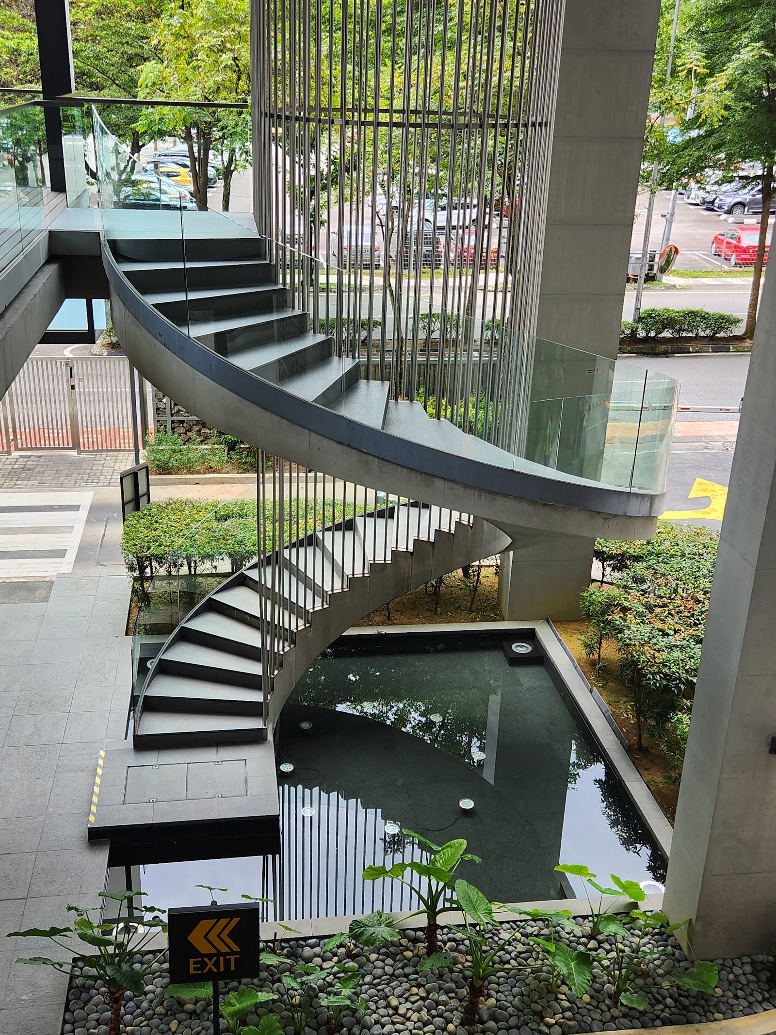 Park Seven: An indoor atrium featuring a modern spiral staircase with metal balustrades, overlooking a landscaped courtyard with a small water feature and greenery.