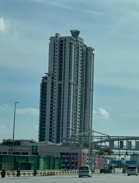 Encorp Strand Residences: A street-level view of the Encorp Strand Residences tower with traffic on the road in the foreground.