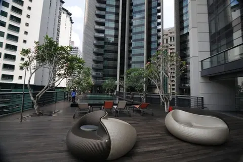 The Troika: A rooftop pool and lounge area with modern furniture and trees, surrounded by high-rise residential towers.