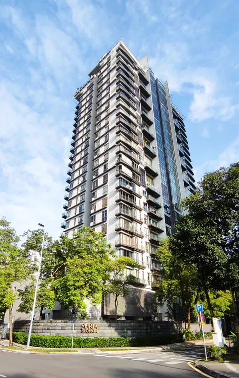 Suria Stonor: A low-angle exterior shot of a high-rise residential building with a stone wall and signage at its base.