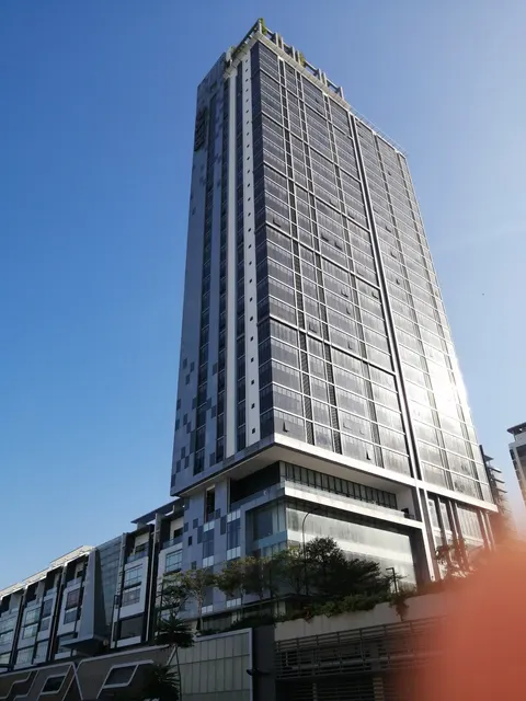 Rev0 @ Aurora Place: A high-angle view of the facade of a tall, modern residential tower against a clear blue sky.