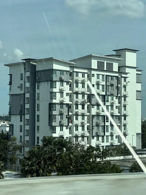 Suria Apartment @ Kota Damansara: A view of the exterior facade of a high-rise apartment building, taken from the side, possibly through a window given the reflection artifacts.