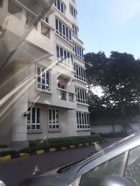 Tara Condominium: The exterior facade of a multi-story residential building with white columns and balconies, viewed from a vehicle with reflections on the windshield.