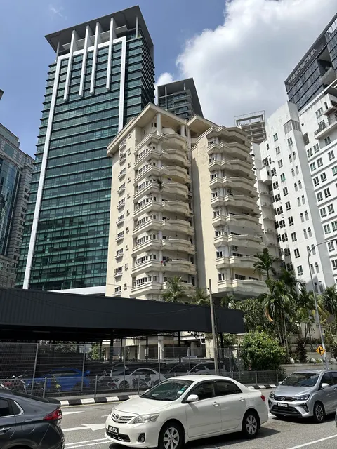 Jelita Court: A street-level view looking up at the facade of a residential building, Jelita Court, set against taller modern towers, with cars parked in the foreground.